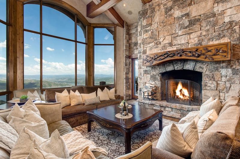 Mountain home great room with stone fireplace and arched window with valley view