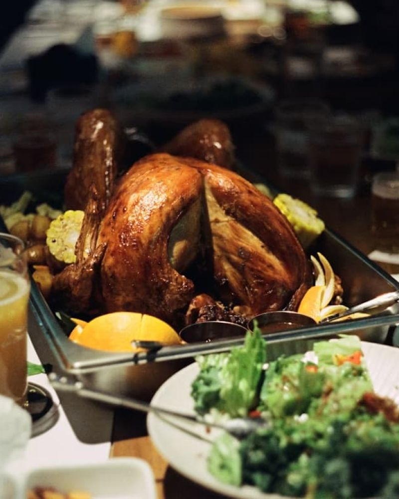 Roasted Thanksgiving turkey on a platter with sides on a long dinner table
