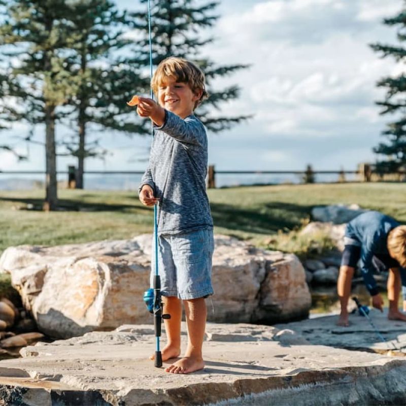 Young boy fishing from a stone patio beside a pond