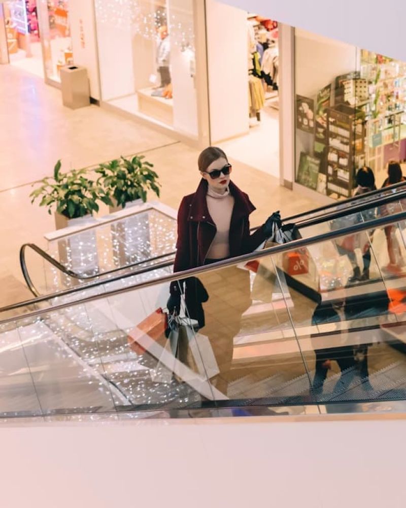 Woman with shopping bags riding an escalator inside a mall