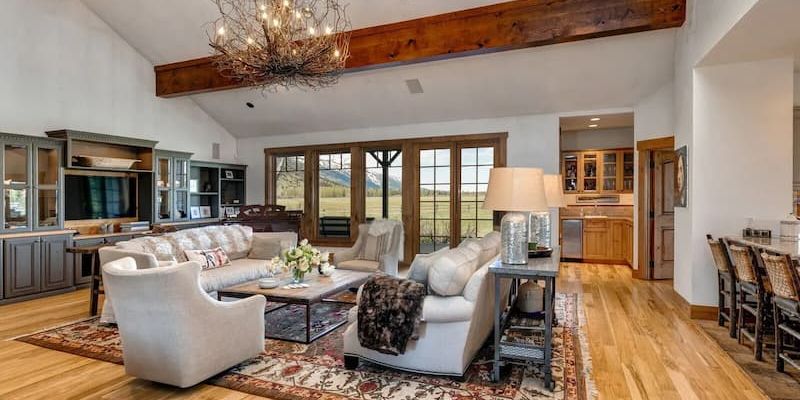 Two-story timber lodge with wraparound porch facing the Teton Range