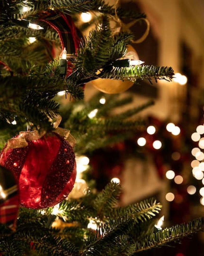 Decorated Christmas tree with red ornaments and ribbon glowing indoors