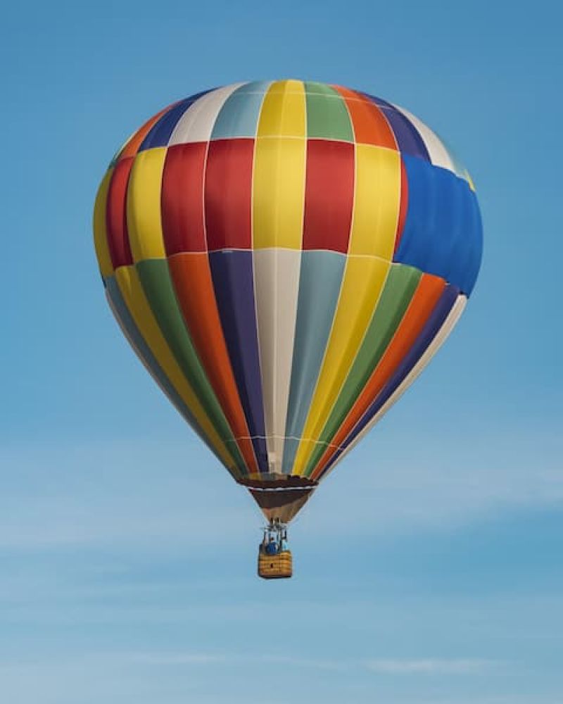 Multicolored striped hot air balloon drifting across a clear blue sky