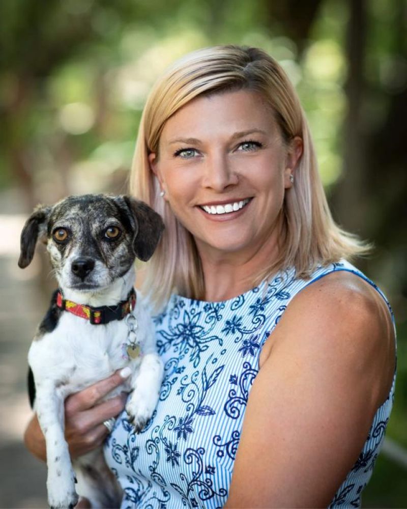 Smiling woman holding a small black and white dog outdoors