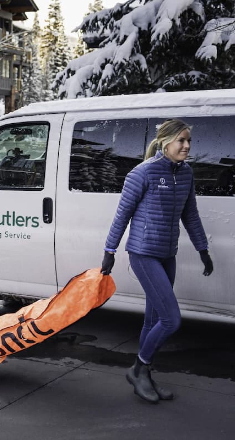 Ski Butlers delivery van with staff member carrying an Insignia ski bag
