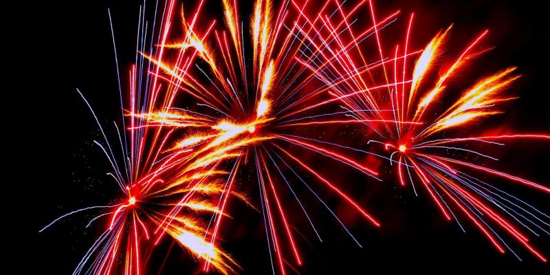 Red and orange fireworks bursting against a black night sky