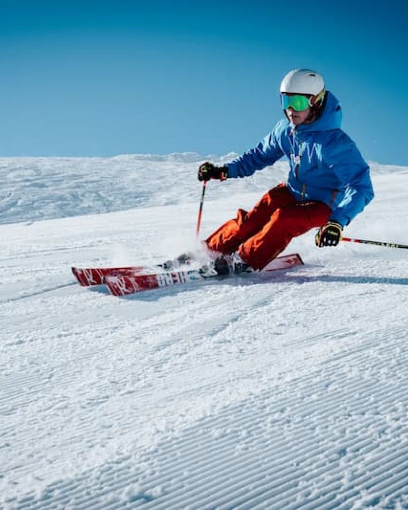 Skier in blue jacket carving a turn down a freshly groomed run