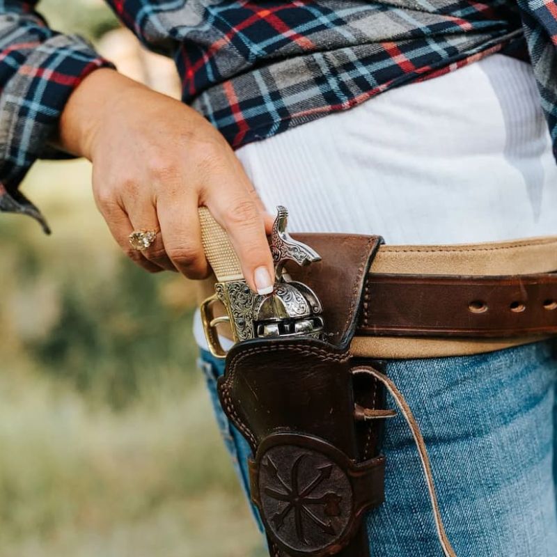 Engraved revolver tucked into a leather western holster on a belt