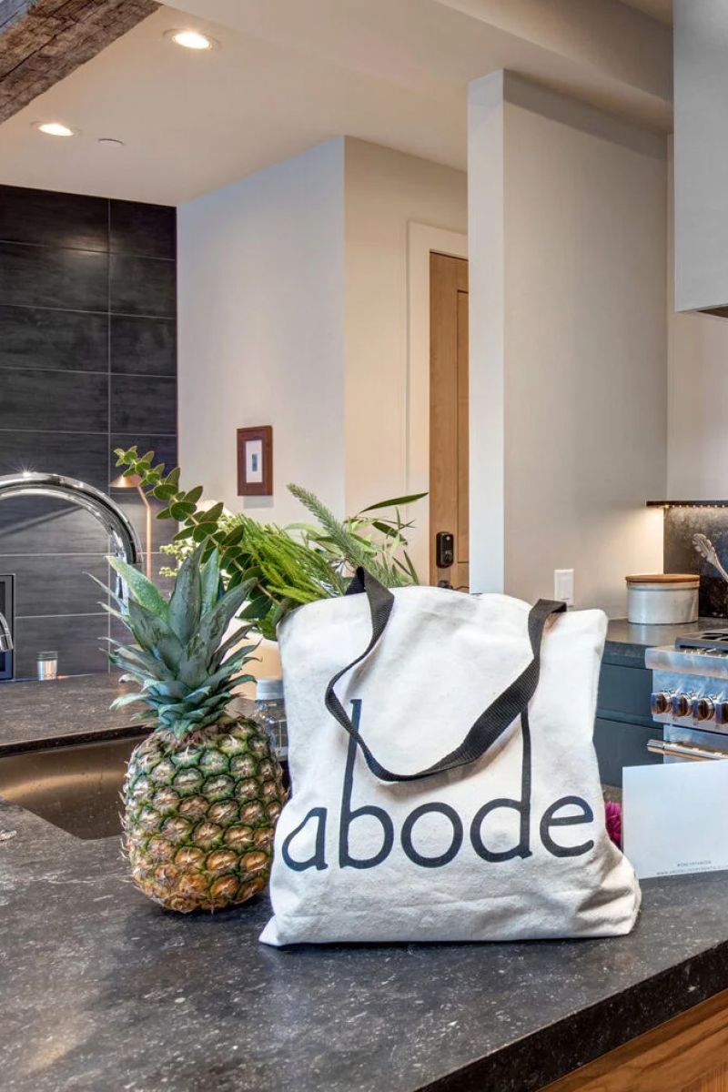 Canvas tote bag with abode logo on a kitchen counter beside a pineapple