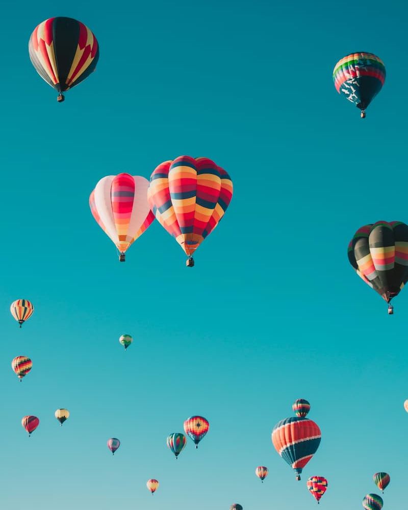 Cluster of colorful hot air balloons drifting against a blue sky