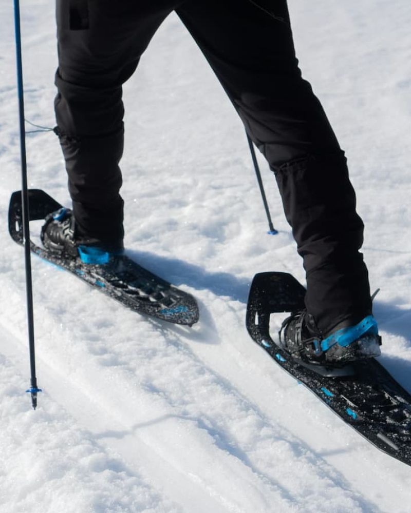 Snowshoer's legs stepping along a packed snow trail with poles