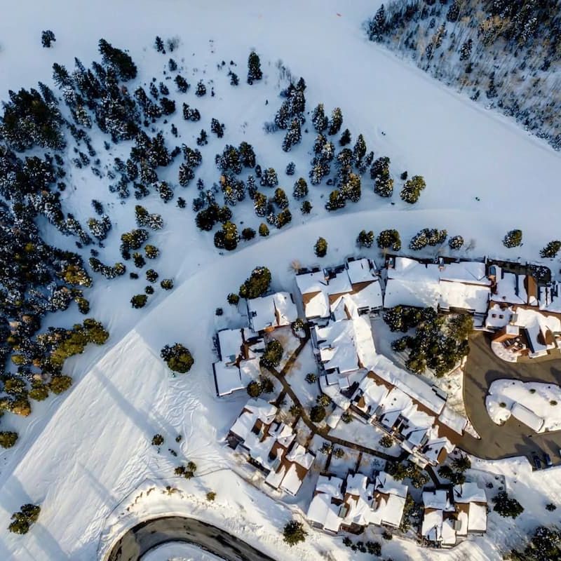 Aerial view of a snow-covered mountain village surrounded by evergreen forest