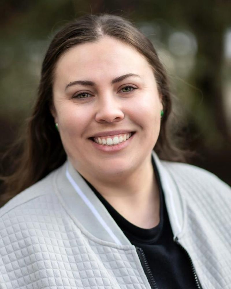 Headshot of a smiling woman in a quilted gray jacket