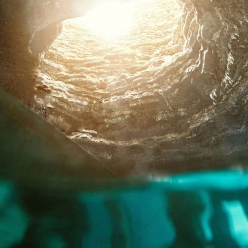Sunlit water rippling at the surface of a swimming pool from below