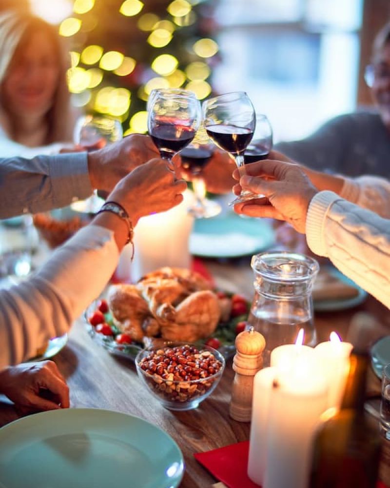 Family clinking red wine glasses over a Thanksgiving dinner table