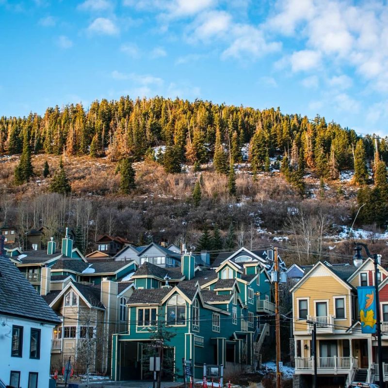 Park City Old Town colorful Victorian homes below a forested hillside at golden hour