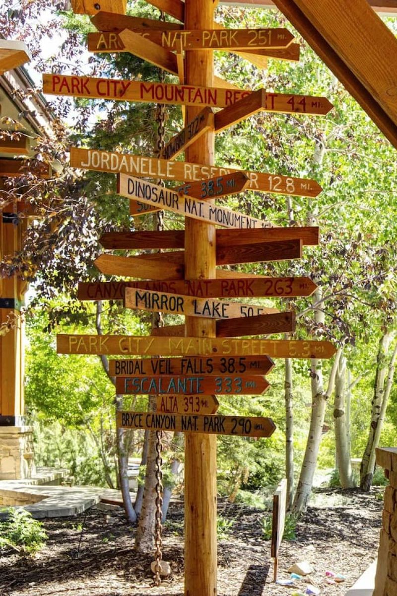 Wooden directional signpost listing distances to Utah parks and landmarks