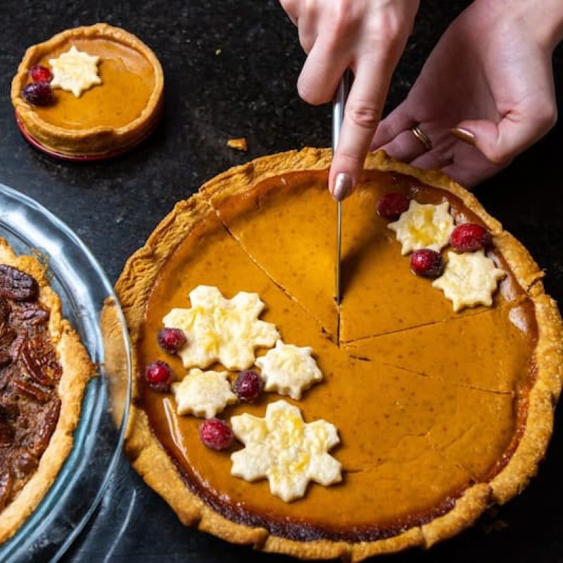 Pumpkin and pecan pies decorated with pastry snowflakes and cranberries