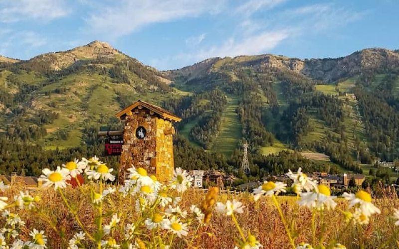 Stone clock tower at the base of Jackson Hole Mountain Resort surrounded by wildflowers