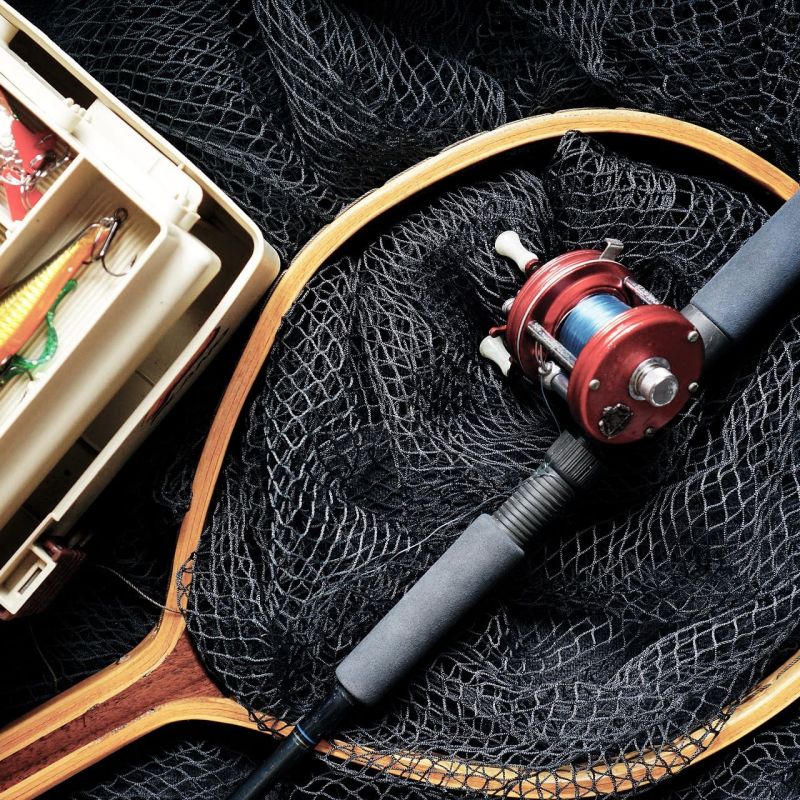 Tackle box with lures and a baitcasting rod resting on a fishing net