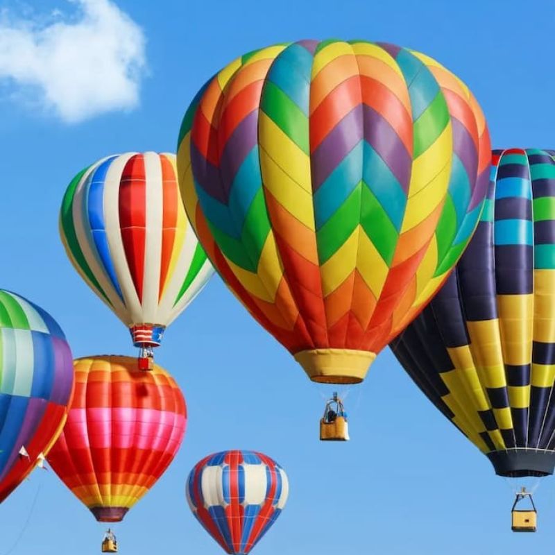 Colorful hot air balloons rising into a clear blue sky