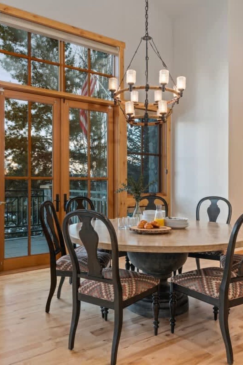 Open-plan dining room with round table, knotty pine cabinetry, and chandelier