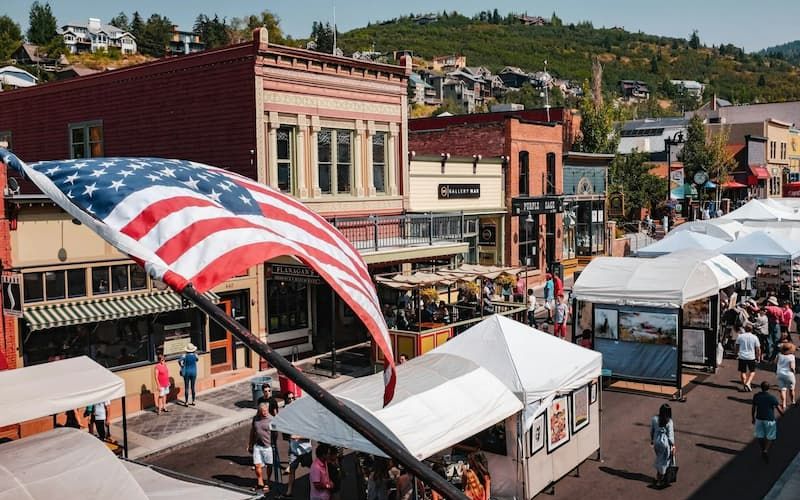 American flag waving above Park City Main Street arts festival tents
