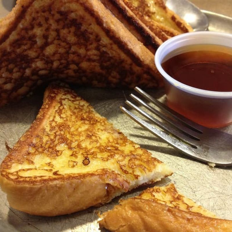 Grilled French toast triangles with maple syrup on a metal tray