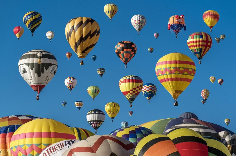 Colorful hot air balloons rising into a clear blue sky at a balloon festival