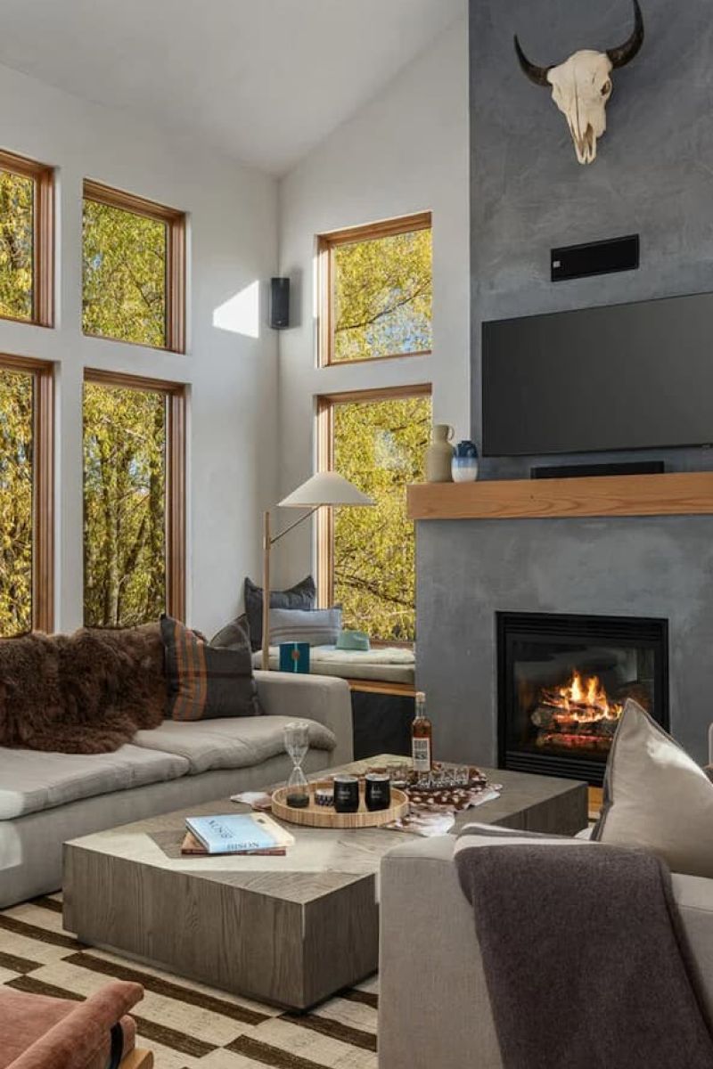 Modern living room with gas fireplace, bison skull, and tall aspen-view windows
