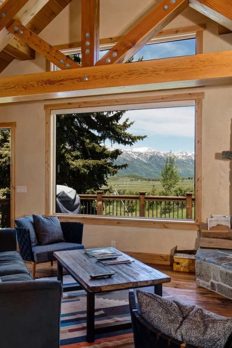 Great room with vaulted timber ceiling and picture window overlooking the Tetons