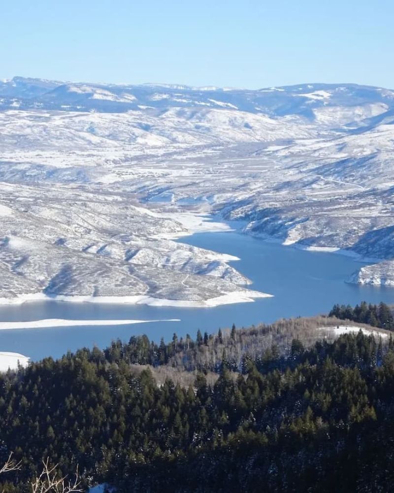 Aerial winter view of a snow-covered reservoir between forested ridges
