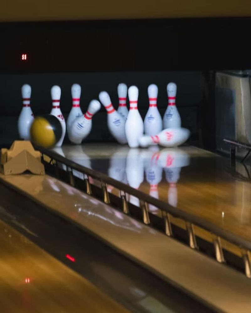 Bowling ball striking pins at the end of a wooden lane