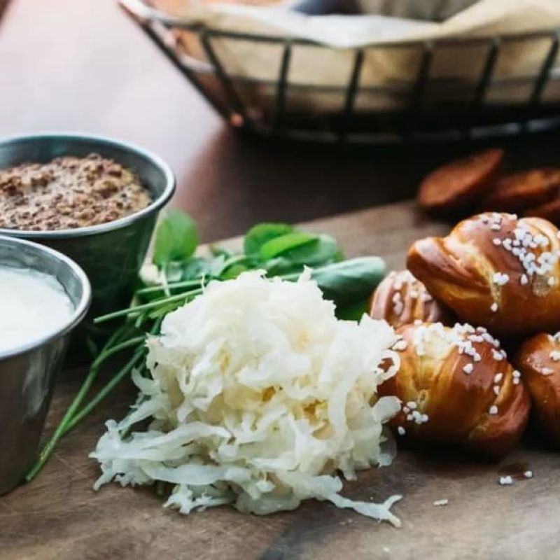 Soft pretzels with mustard, sauerkraut, and dipping sauce on a wood board