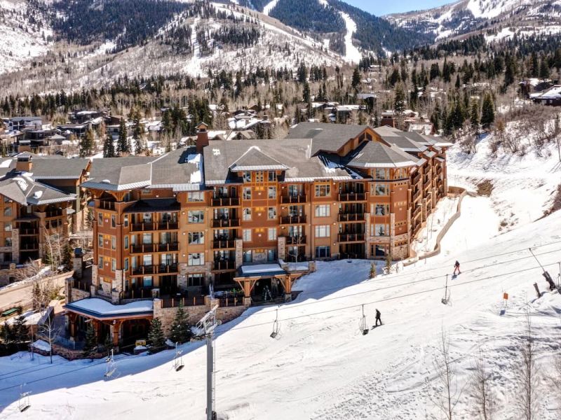 Slopeside Park City condominium building with skiers descending the run beside it