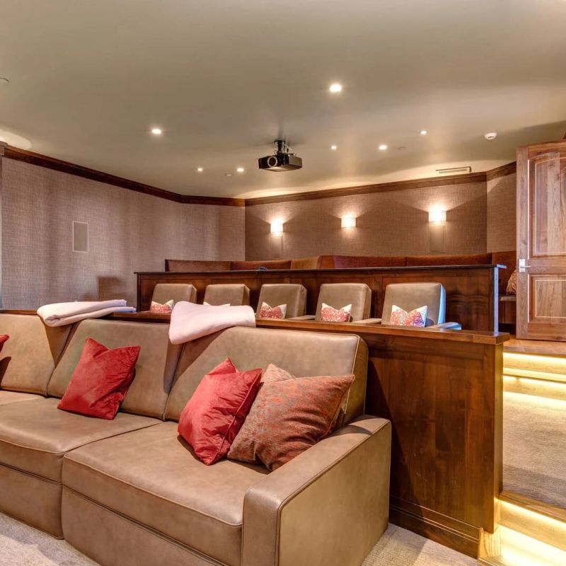 Home theater with tiered leather seating, red pillows, and projector