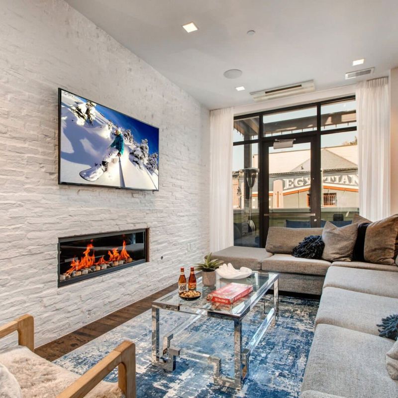 Modern living room with linear gas fireplace, white stone wall, and wall-mounted TV