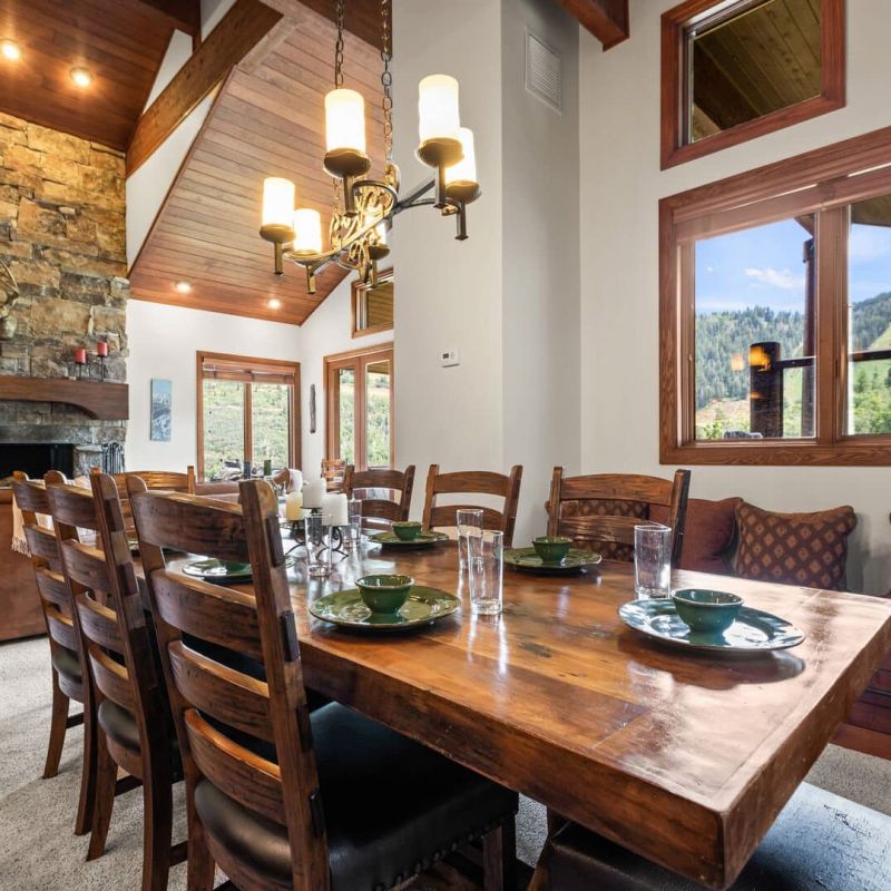 Dining room with long wood table, chandelier, and stone fireplace