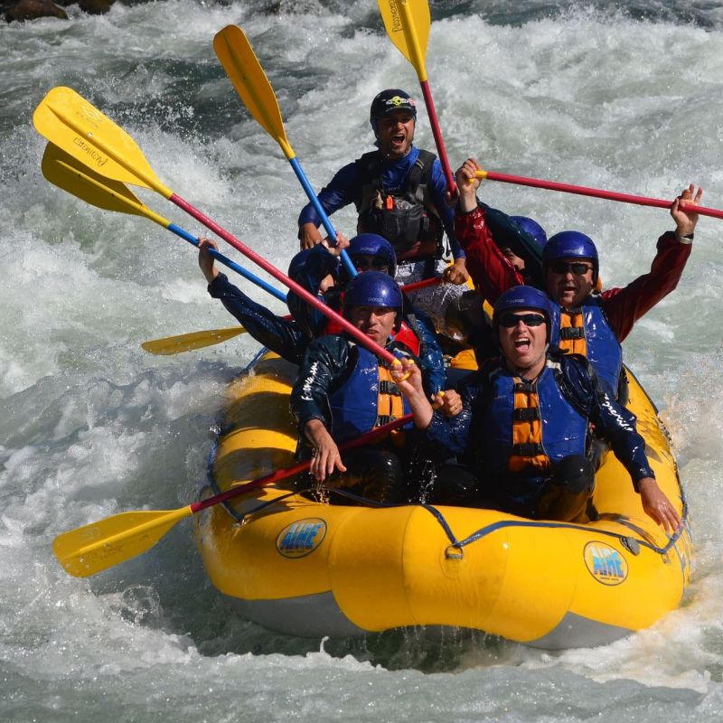 Whitewater rafting team paddling through churning rapids in a yellow raft