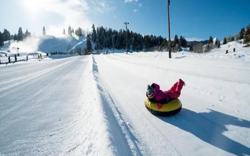 Child sliding down a snow tubing lane on a sunny winter day
