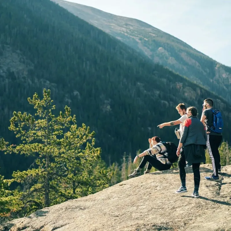 Group of hikers on a granite outcrop overlooking a forested mountain valley