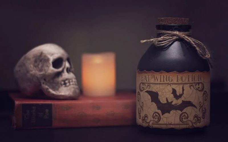 Halloween still life with a skull, candle, and bat wing potion bottle