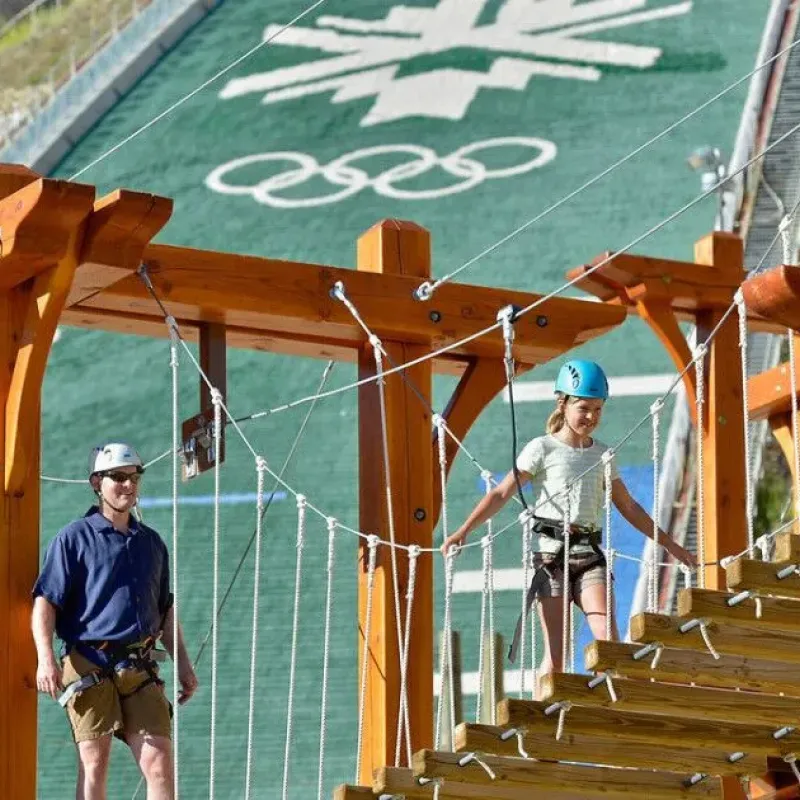 Visitors on the ropes course at Utah Olympic Park in front of the ski jump