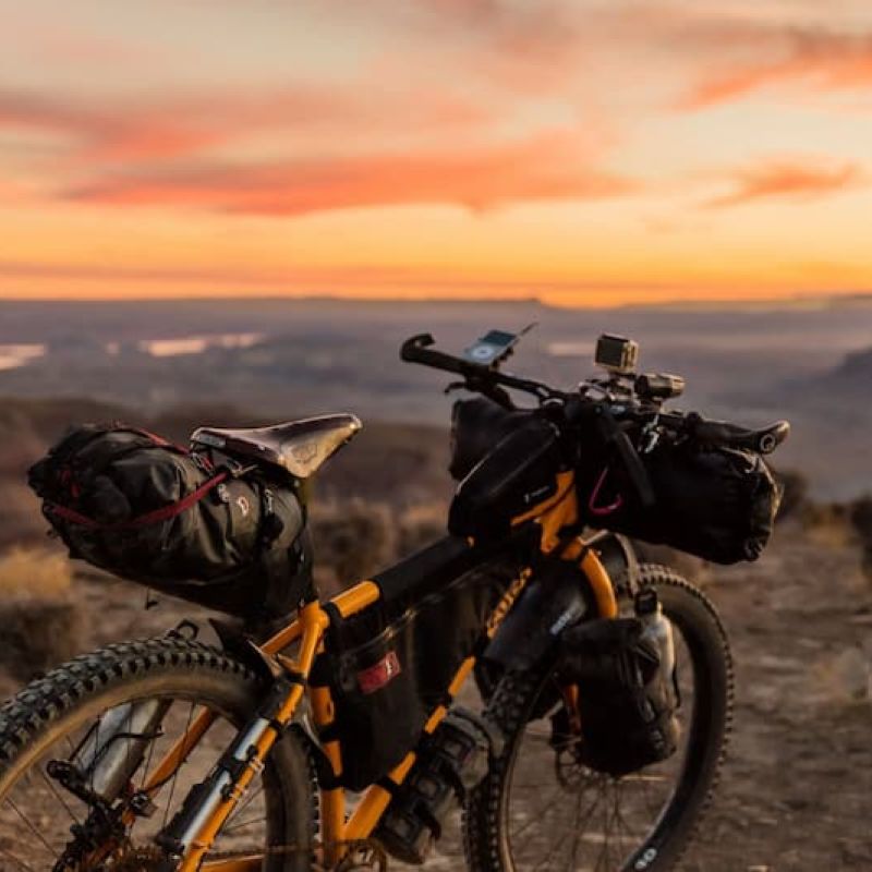 Loaded bikepacking rig parked on a desert overlook at sunset