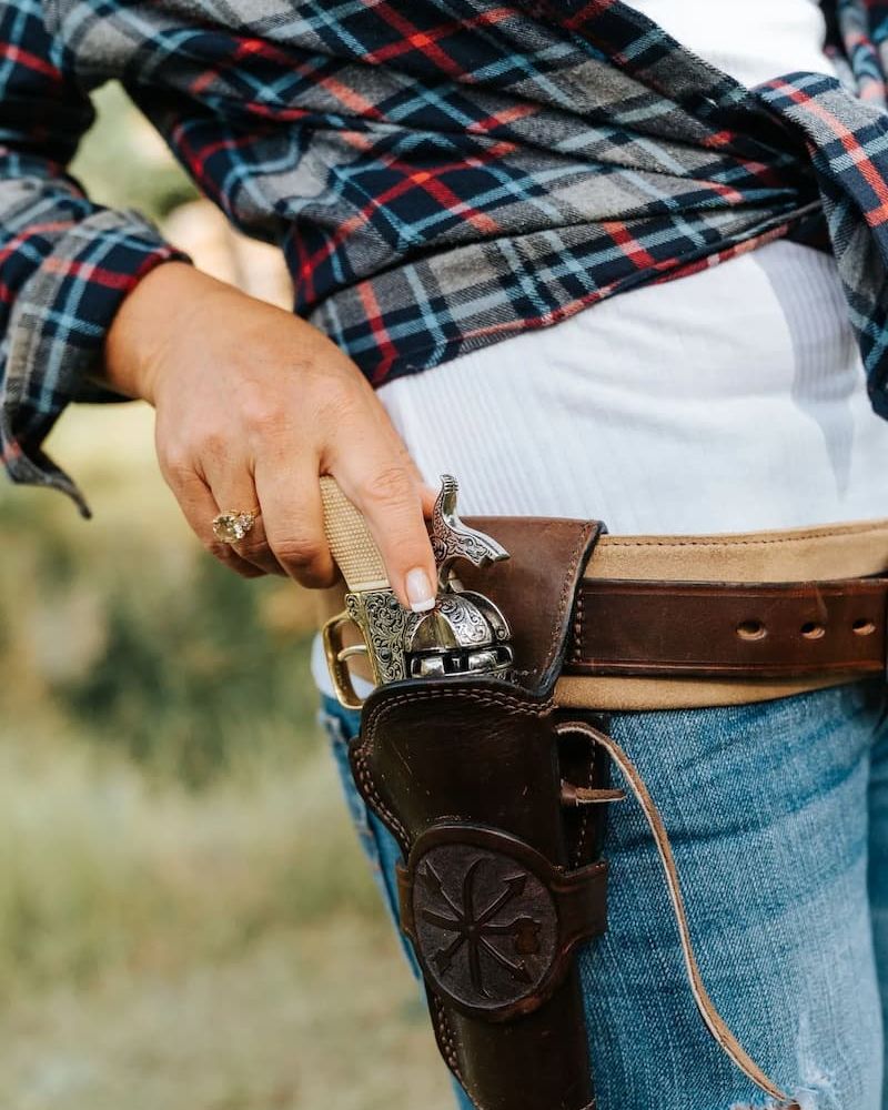 Western-style revolver holstered on a leather belt with plaid shirt