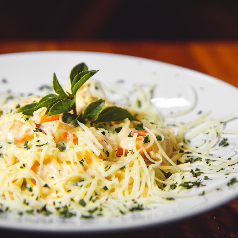 Creamy angel hair pasta garnished with mint on a white plate