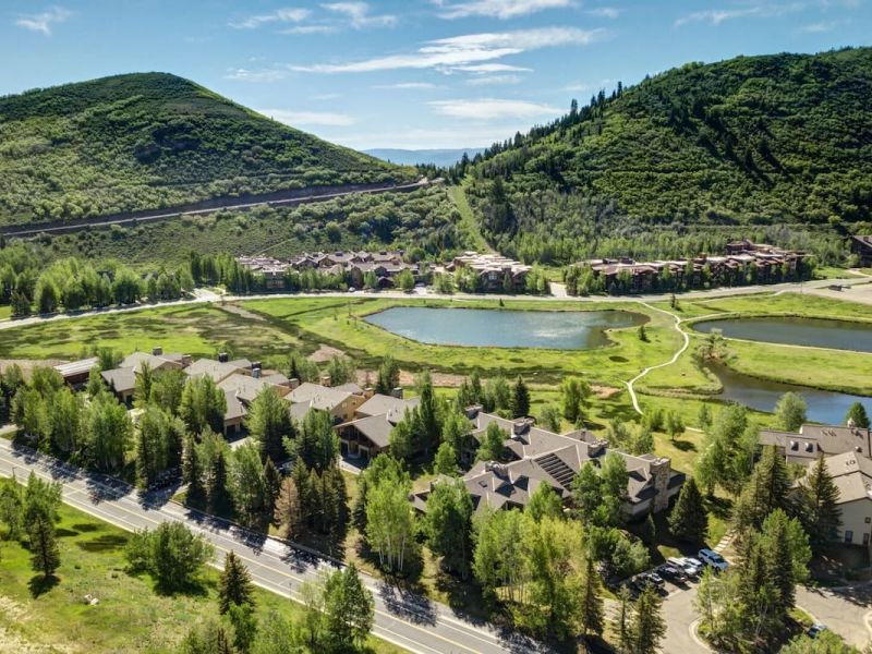 Aerial view of a Park City condominium community beside a small pond and green hillsides