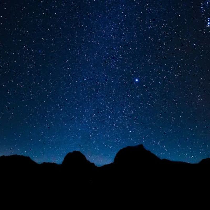 Star-filled night sky over silhouetted desert rock formations