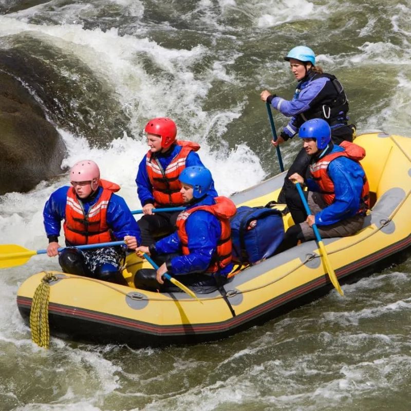 Whitewater rafting team paddling a yellow raft through rapids