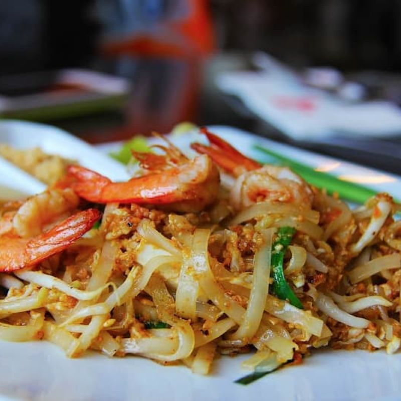 Plate of pad Thai noodles topped with shrimp and scallions
